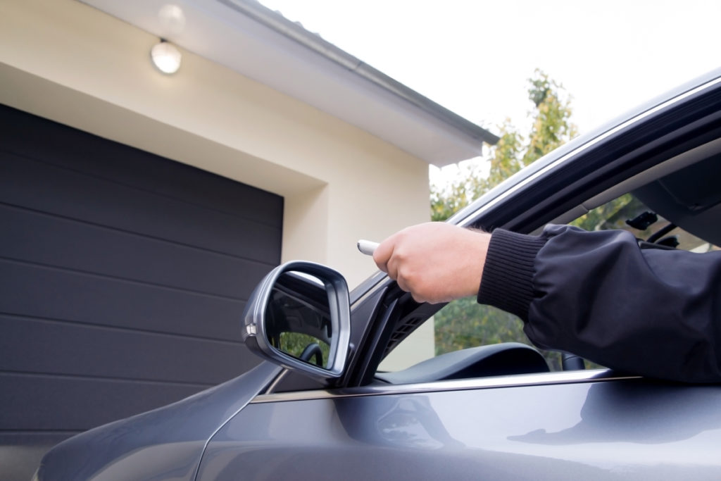 Man using a garage door opener in his driveway